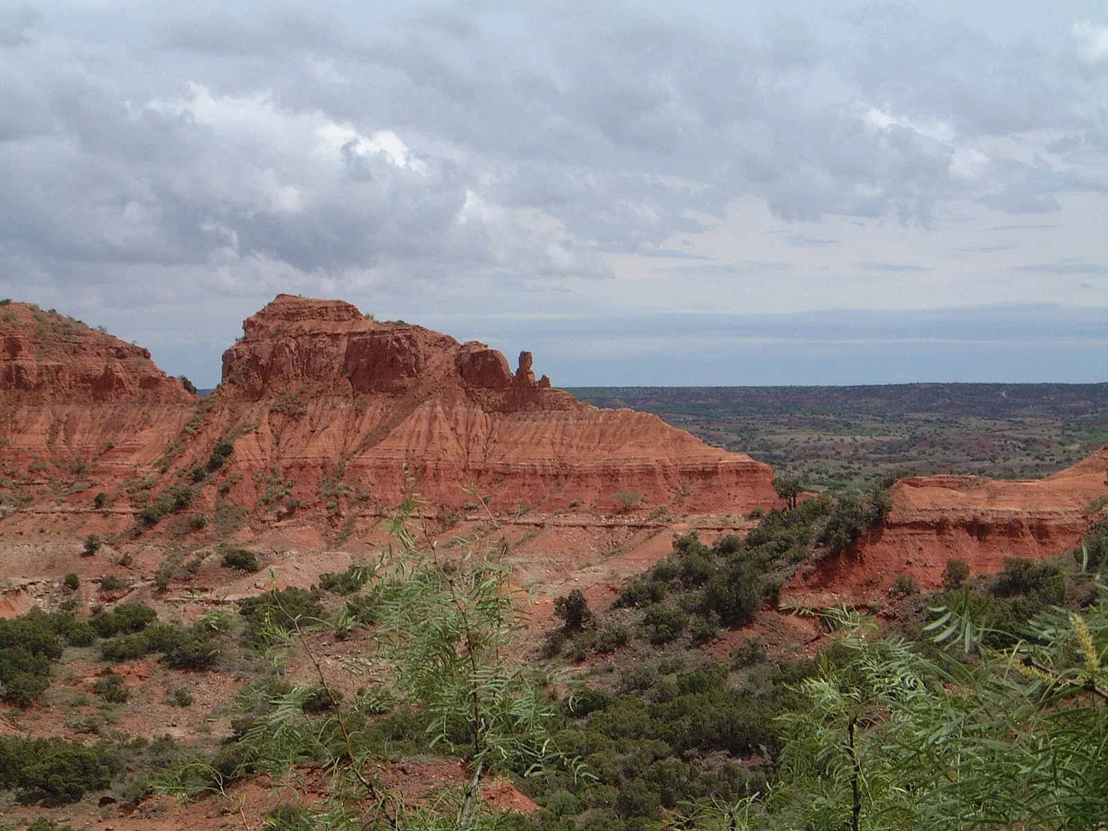 Red sandstone ridge with juniper below and flat Caprock country beyond