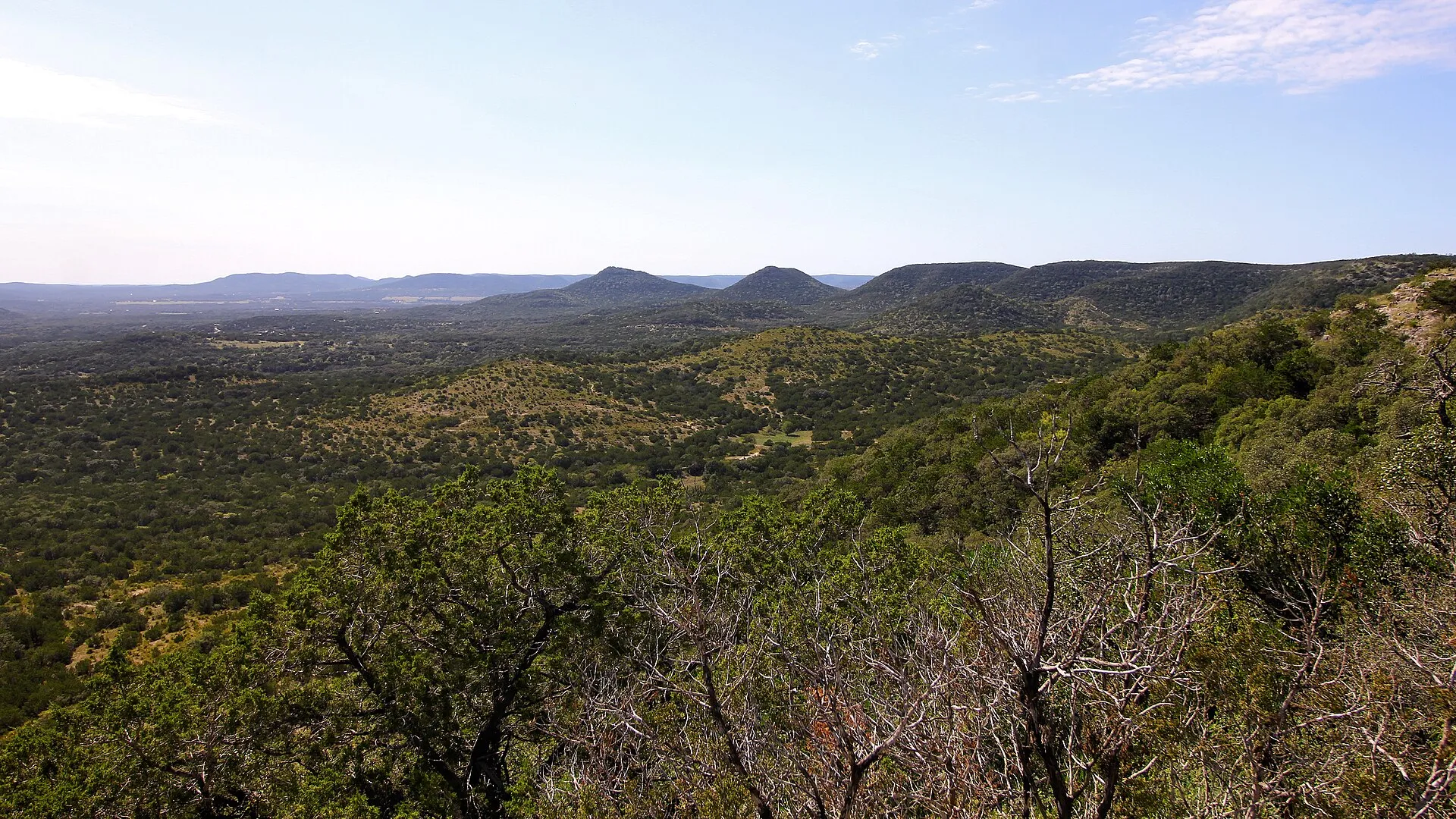 Wooded Hill Country hills rolling to the horizon under a clear sky