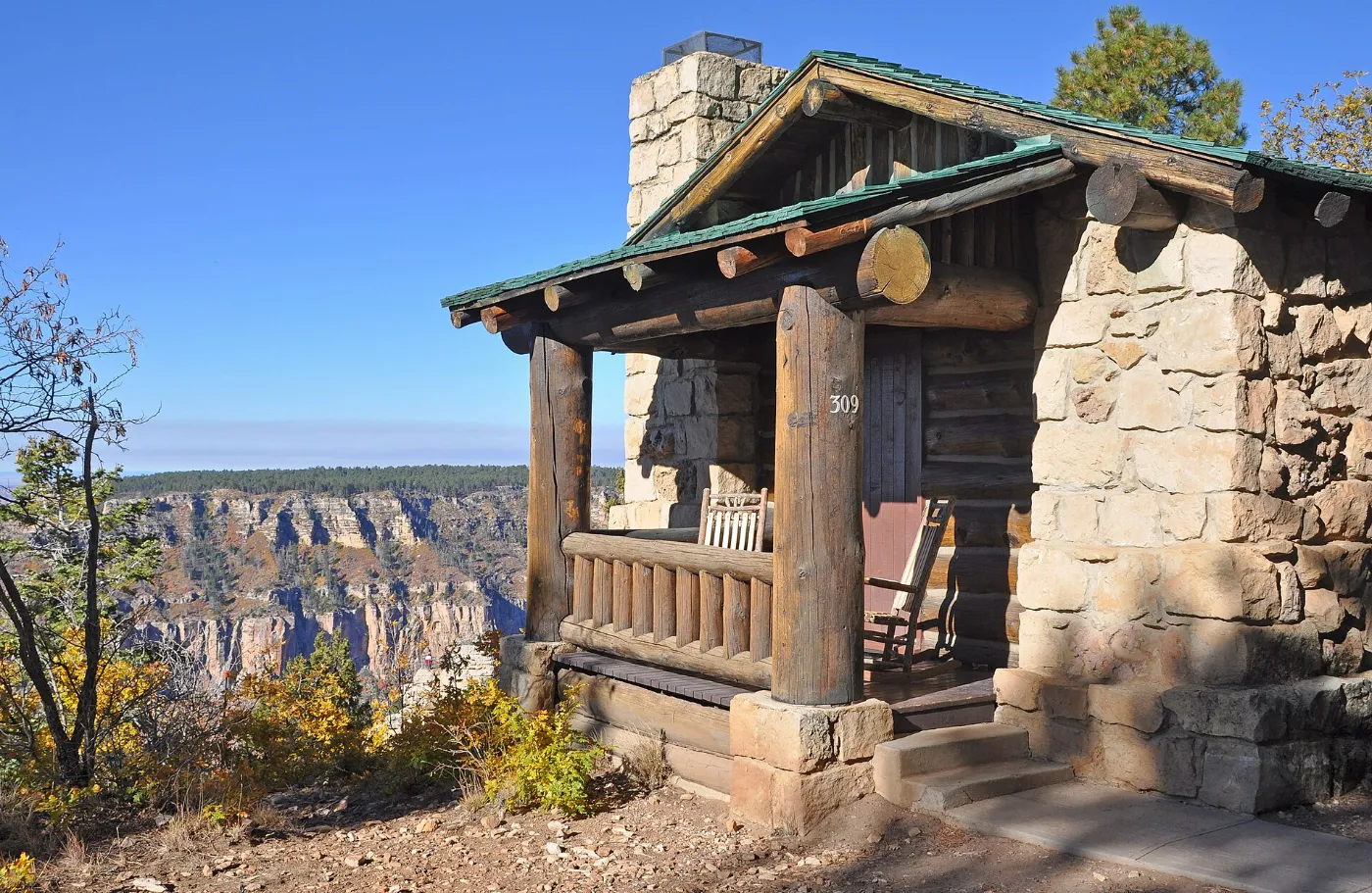 Stone and log guest cabin with a covered front porch and rocking chair