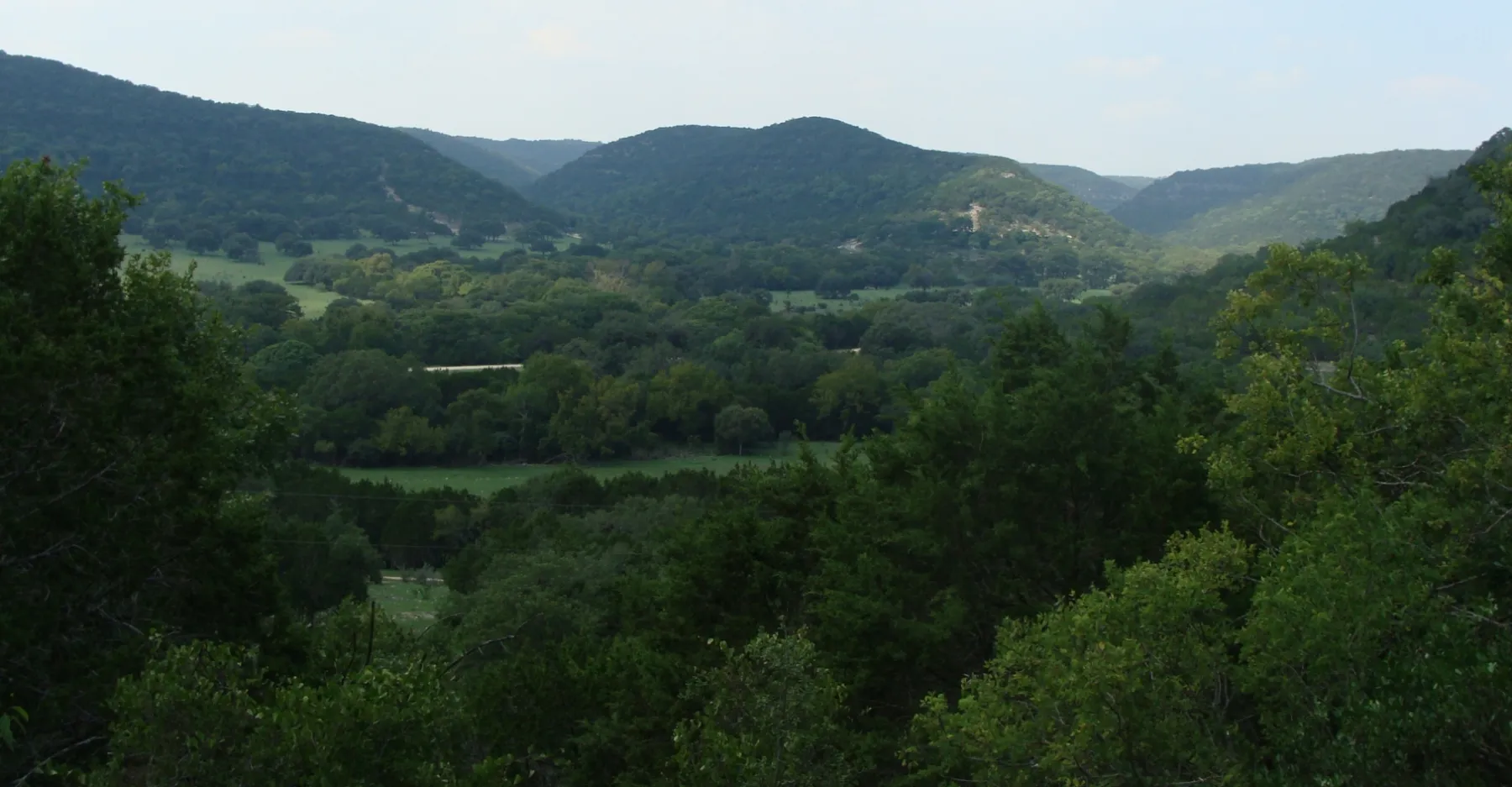Green Hill Country valley with wooded cedar and oak ridges rolling into the distance