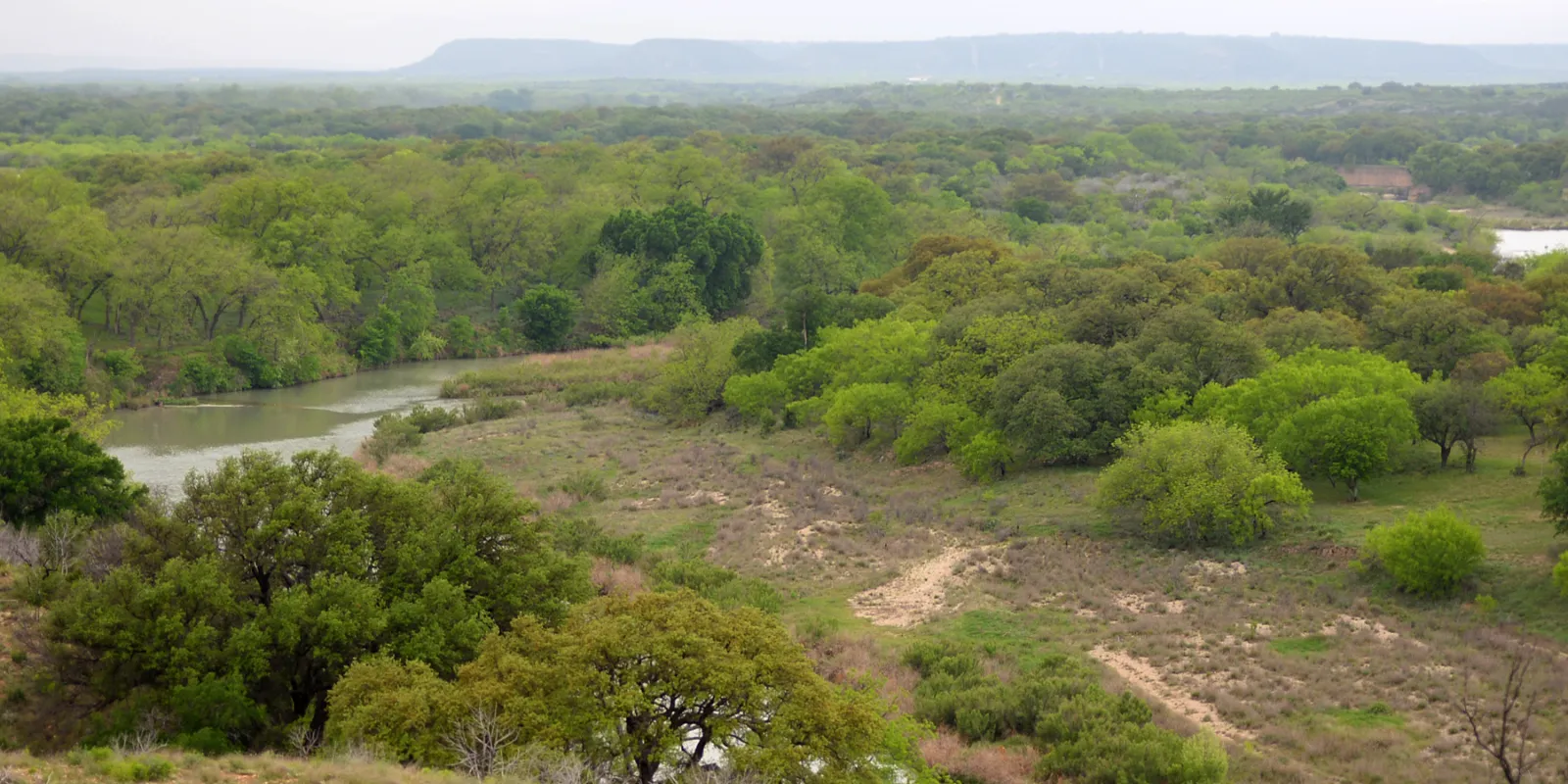 Clear Hill Country river winding through green oak and brush country
